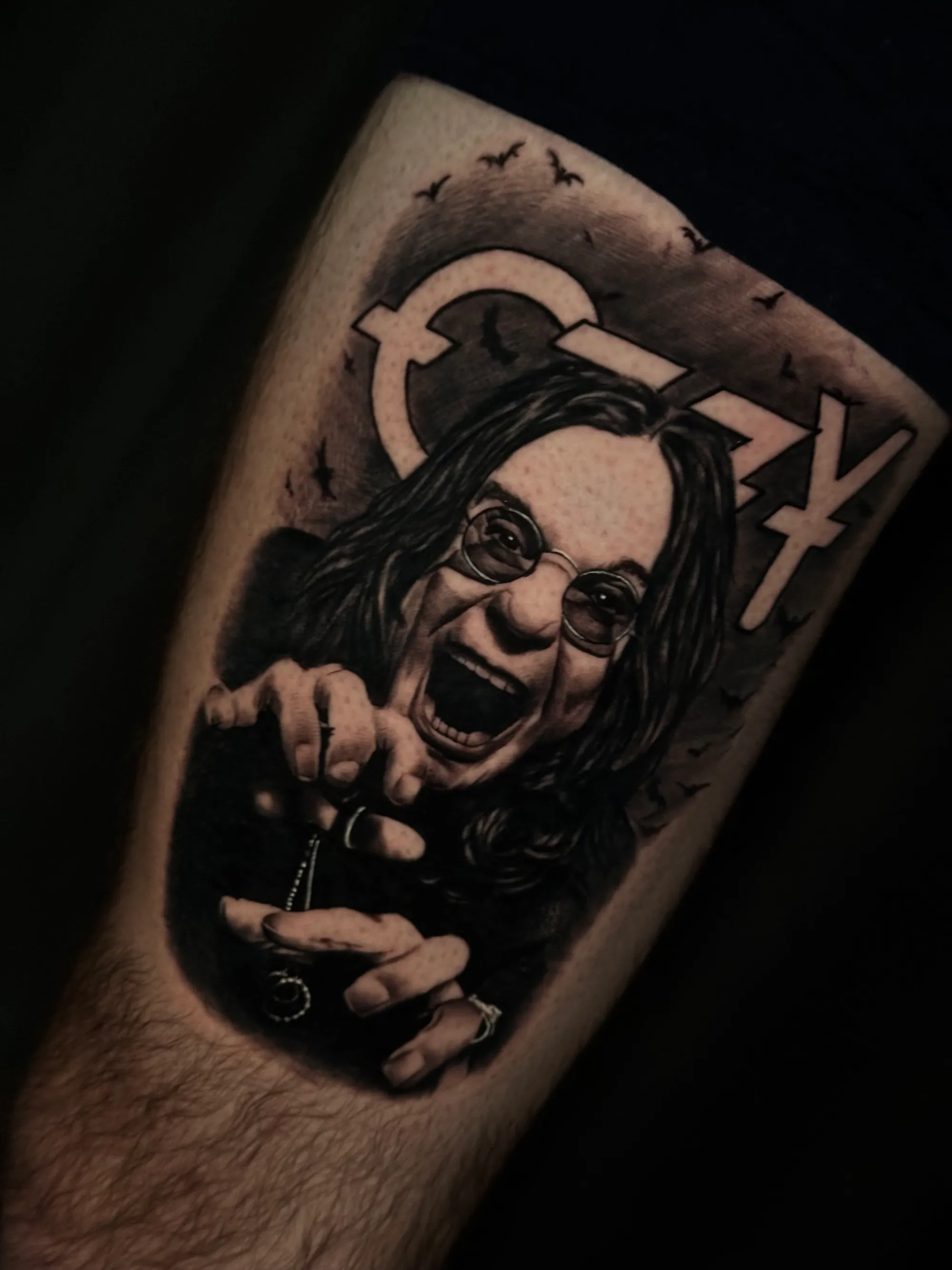 Realistična crno-bela tetovaža portreta Ozija Osborna sa šišmišima i natpisom na podlaktici, Dropz Tattoo Studio Niš