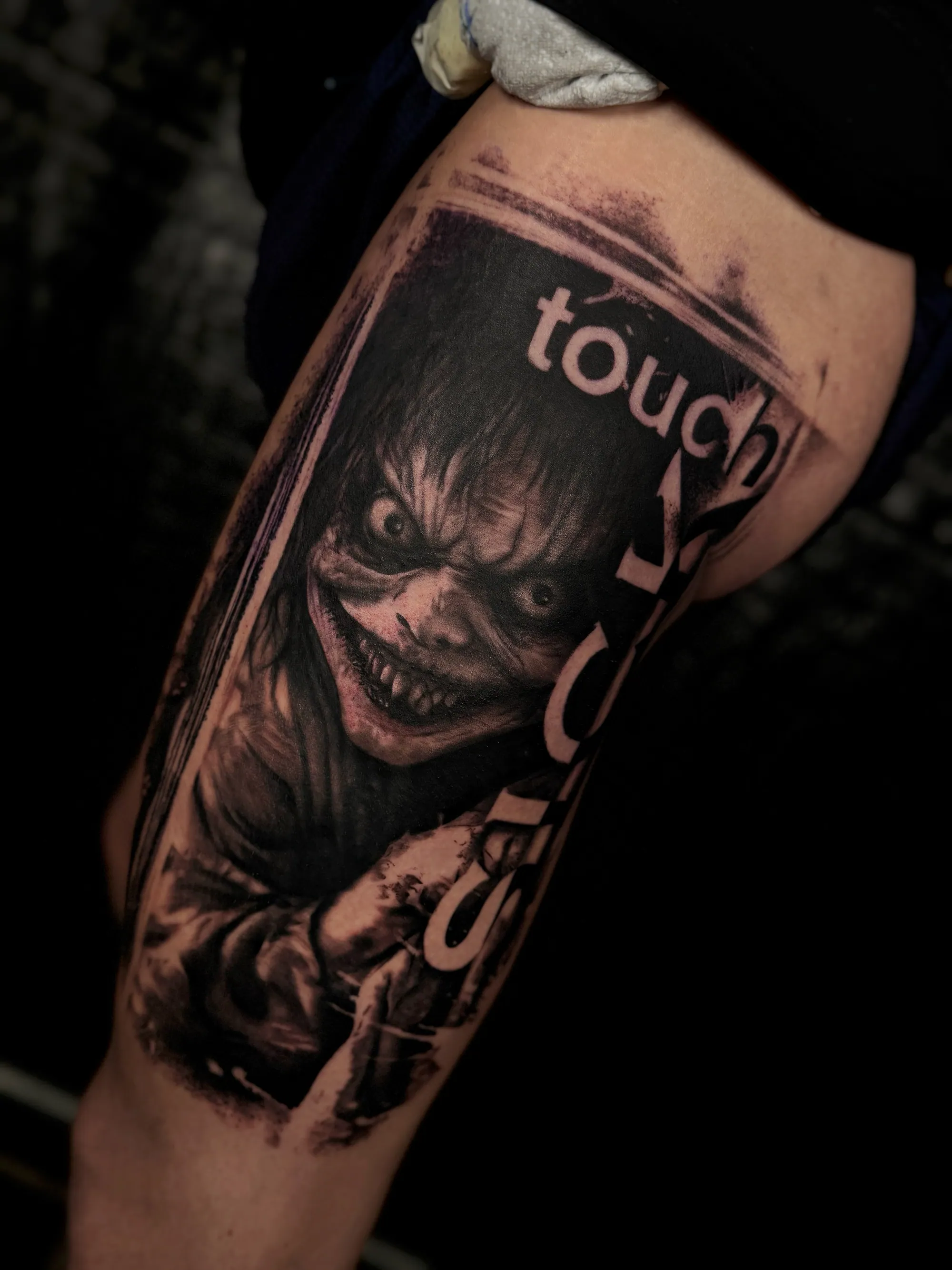 Realistična crno-bela horor tetovaža zastrašujućeg lica sa  natpisom "Sick Touch" na podlaktici, Dropz Tattoo Studio Niš