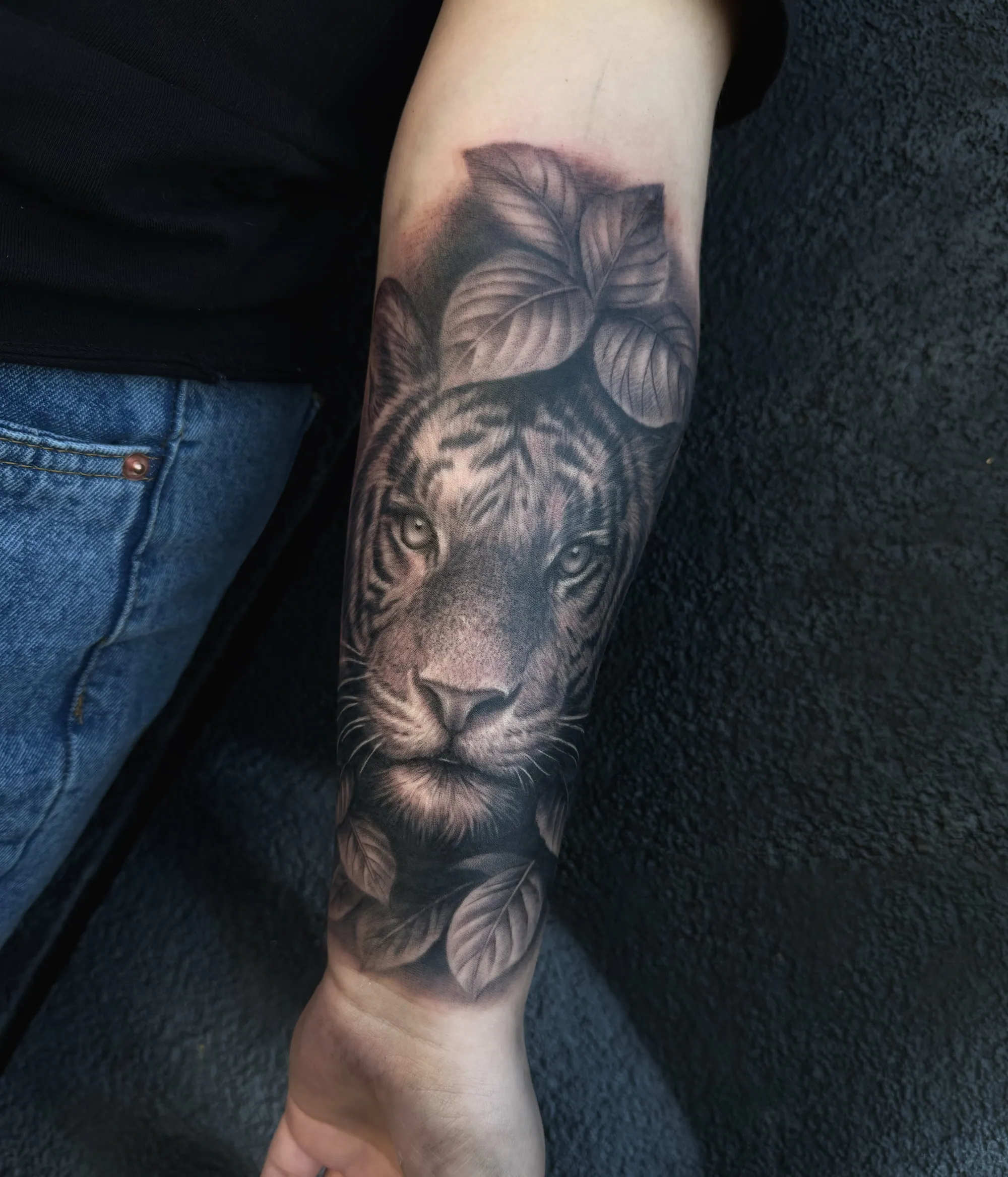 Realistična black and grey tetovaža tigrove glave sa lišćem na  podlaktici, Dropz Tattoo Studio Niš