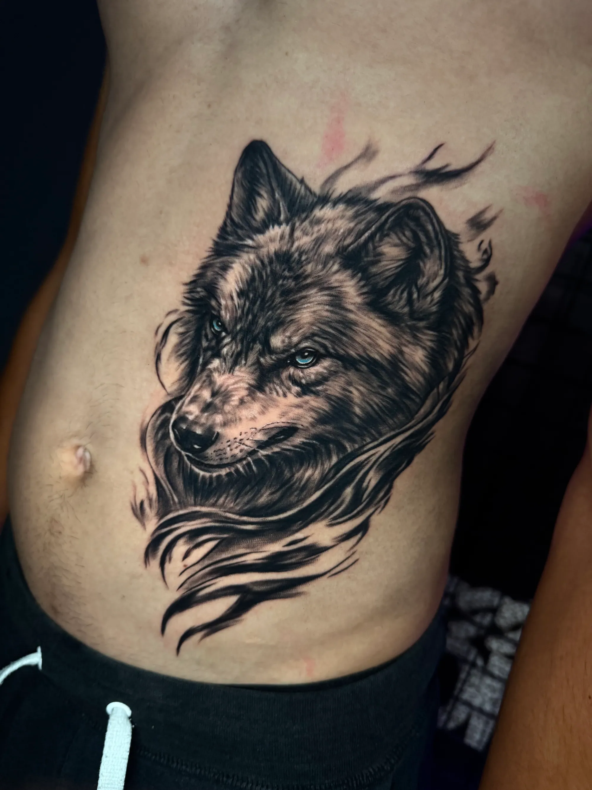Realistična tetovaža glave vuka sa plavim očima na rebrima,  Dropz Tattoo Studio Niš
